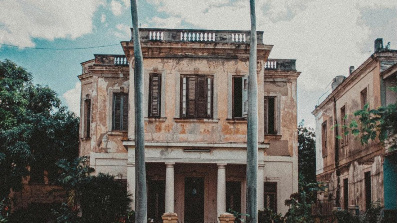 Historic house with a portico and royal palms in Havana